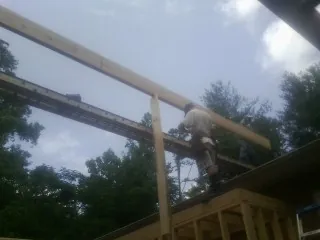 Carpenter setting a ridge beam over a new addition frame — Ice Dam Removal by Roofing Brothers in Lawrenceville