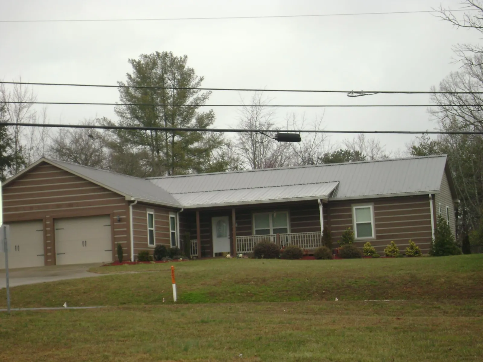 Gray metal roof on a log sided ranch home with a front porch in Lawrenceville