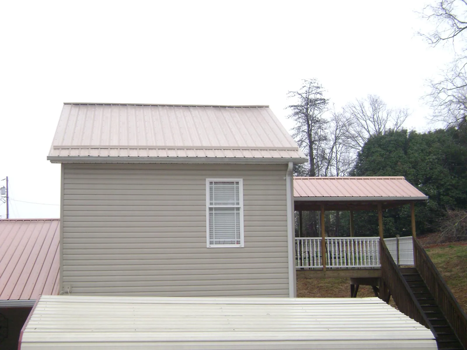 Tan metal roofs on a two story addition and attached porch, from a Roof Replacement job in Lawrenceville