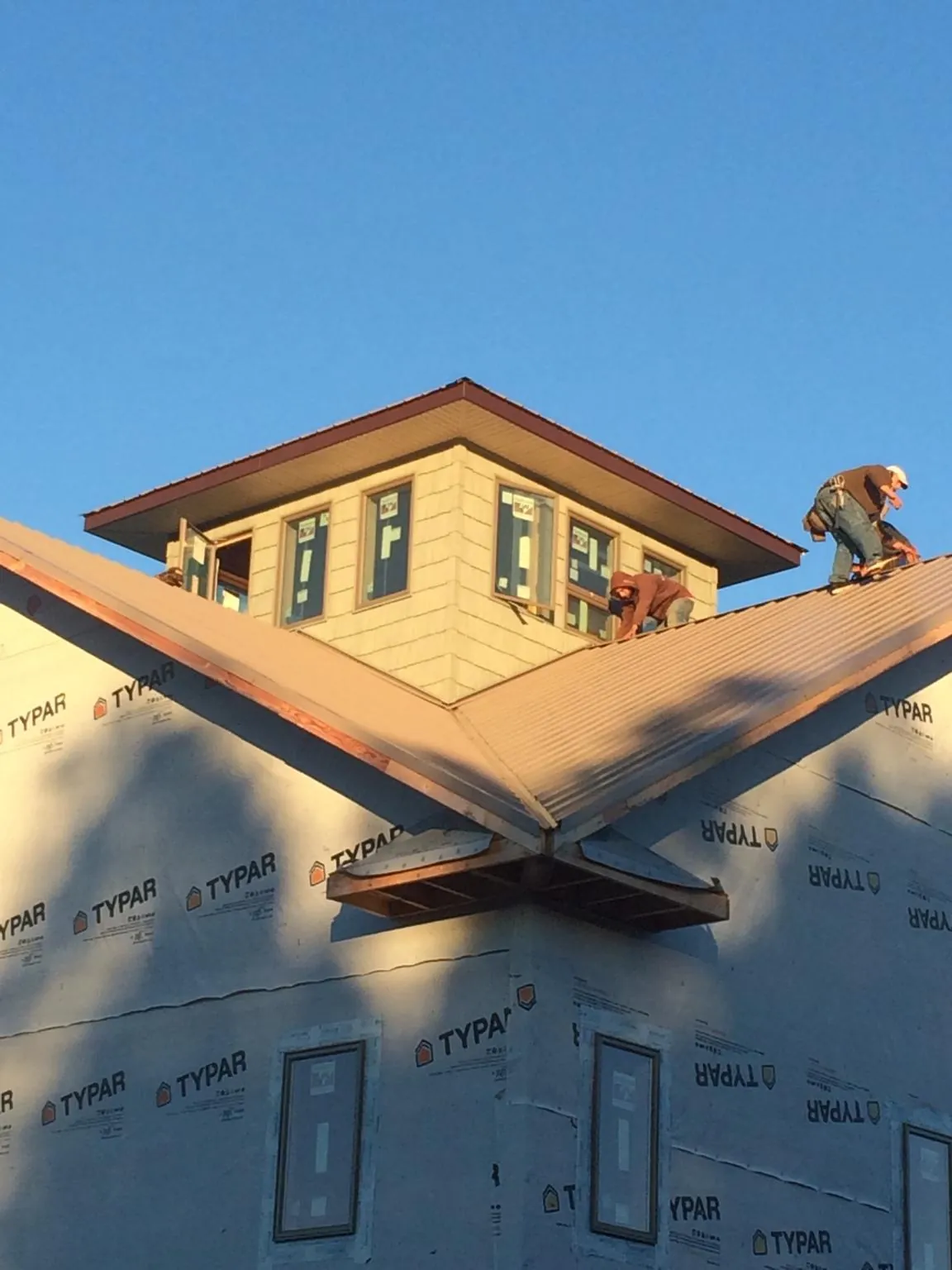 Roofers working around a rooftop cupola on a new metal roof at sunset — Roof Waterproofing in Lawrenceville by Roofing Brothers